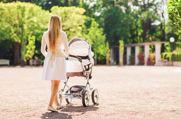 mom taking newborn on a walk in stroller with basinette