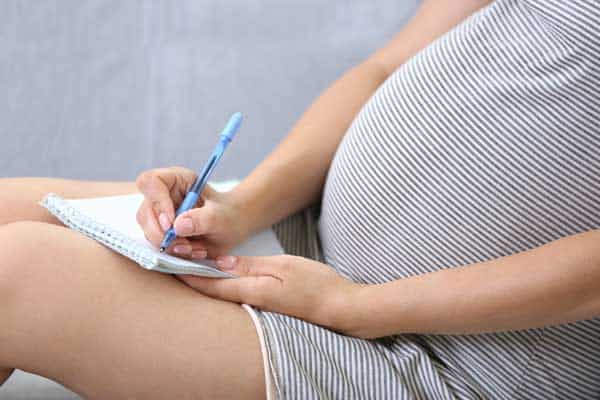 pregnant woman writing what to pack in your baby's checklist