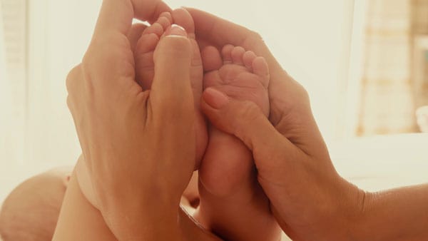 mom rubbing baby's toes to wake them up 