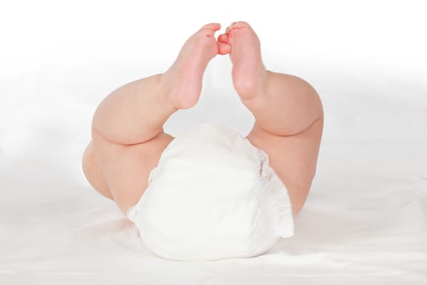 white disposable diaper and baby legs on white background