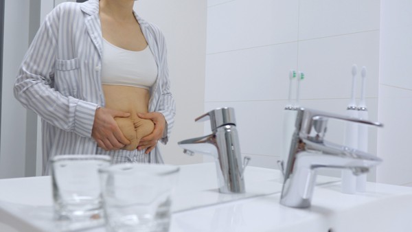 postpartum mom holding belly in front of mirror