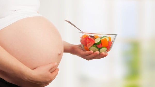 pregnant woman holding salad